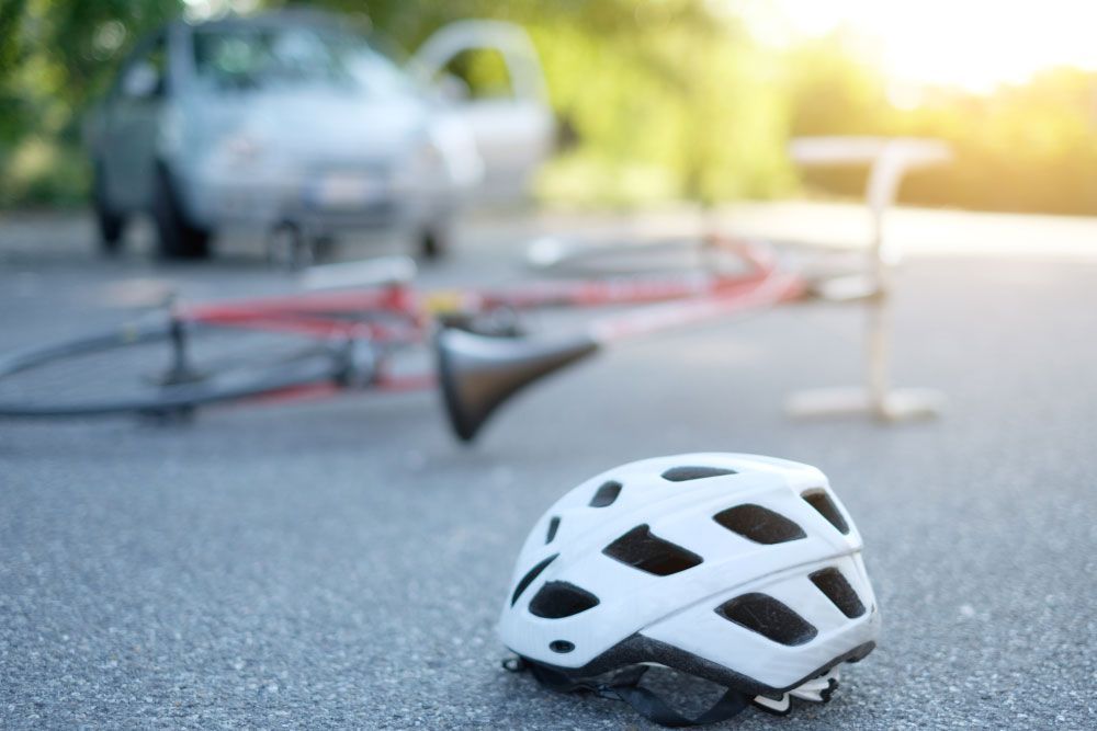 Bicycle helmet lying on the road beside a car after a pedestrian and bicycle accident in Pittsburgh, PA