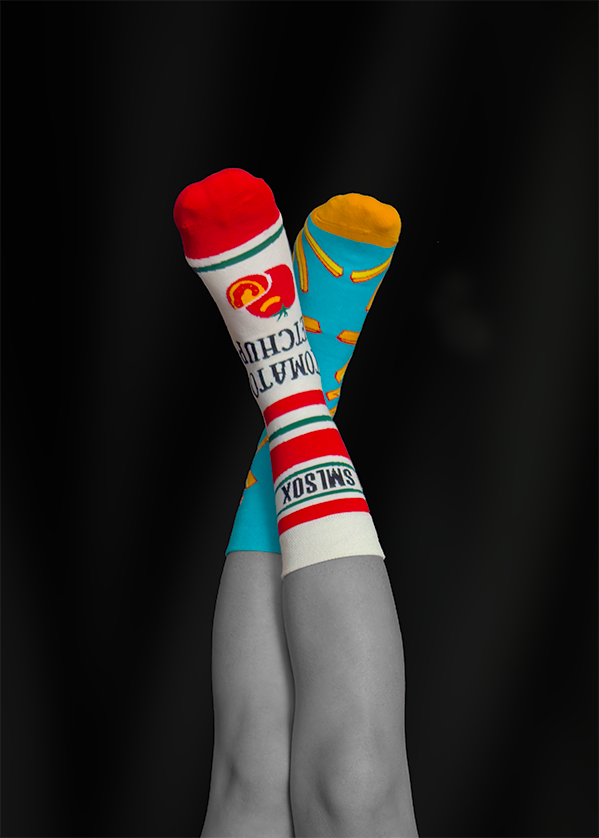 Crossed legs wearing colorful socks against a black background. One sock reads
