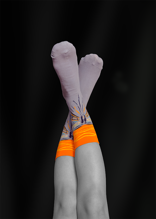 Legs crossed, feet up, wearing orange and patterned socks, against a black background.