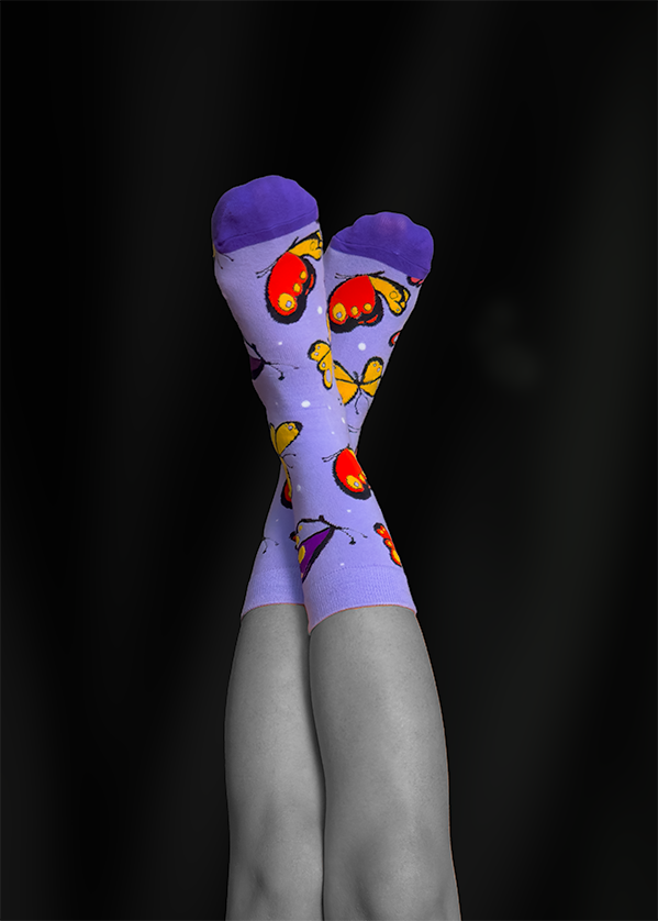 Purple socks with butterfly pattern on black and white legs, crossed against a black background.