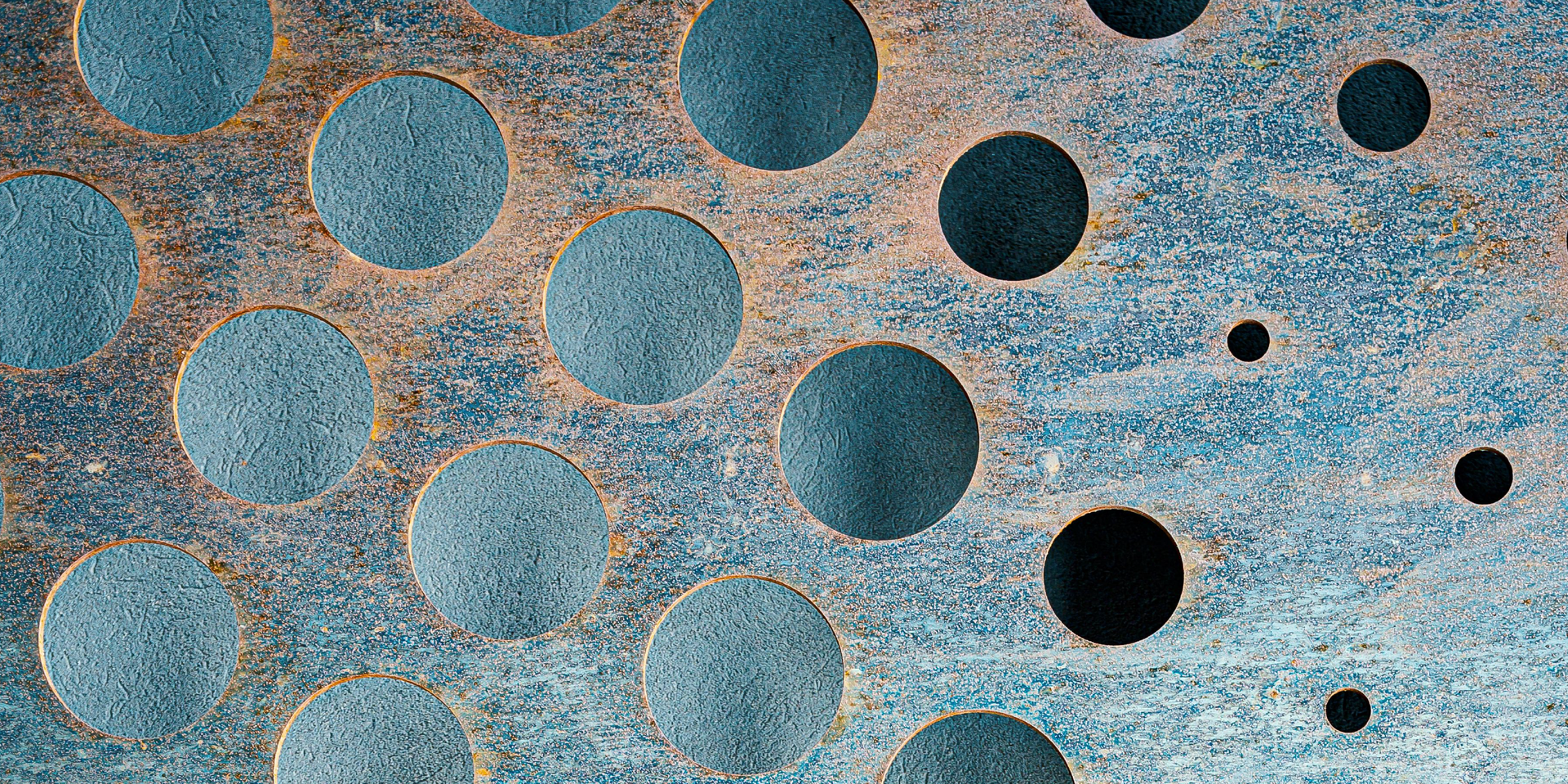 Close-up of weathered blue-green metal with perforated circular holes, symbolizing audit gaps and we
