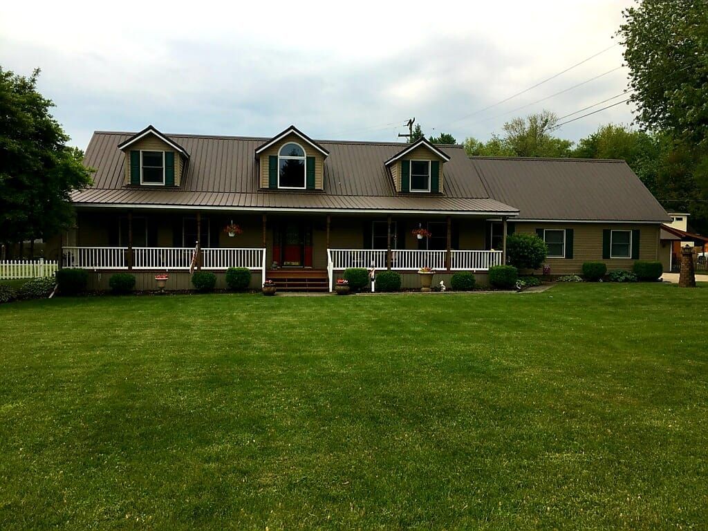 Green metal roof with grasses in front yard— Croswell, MI — Parraghi Roofing & Sheet Metal, LLC