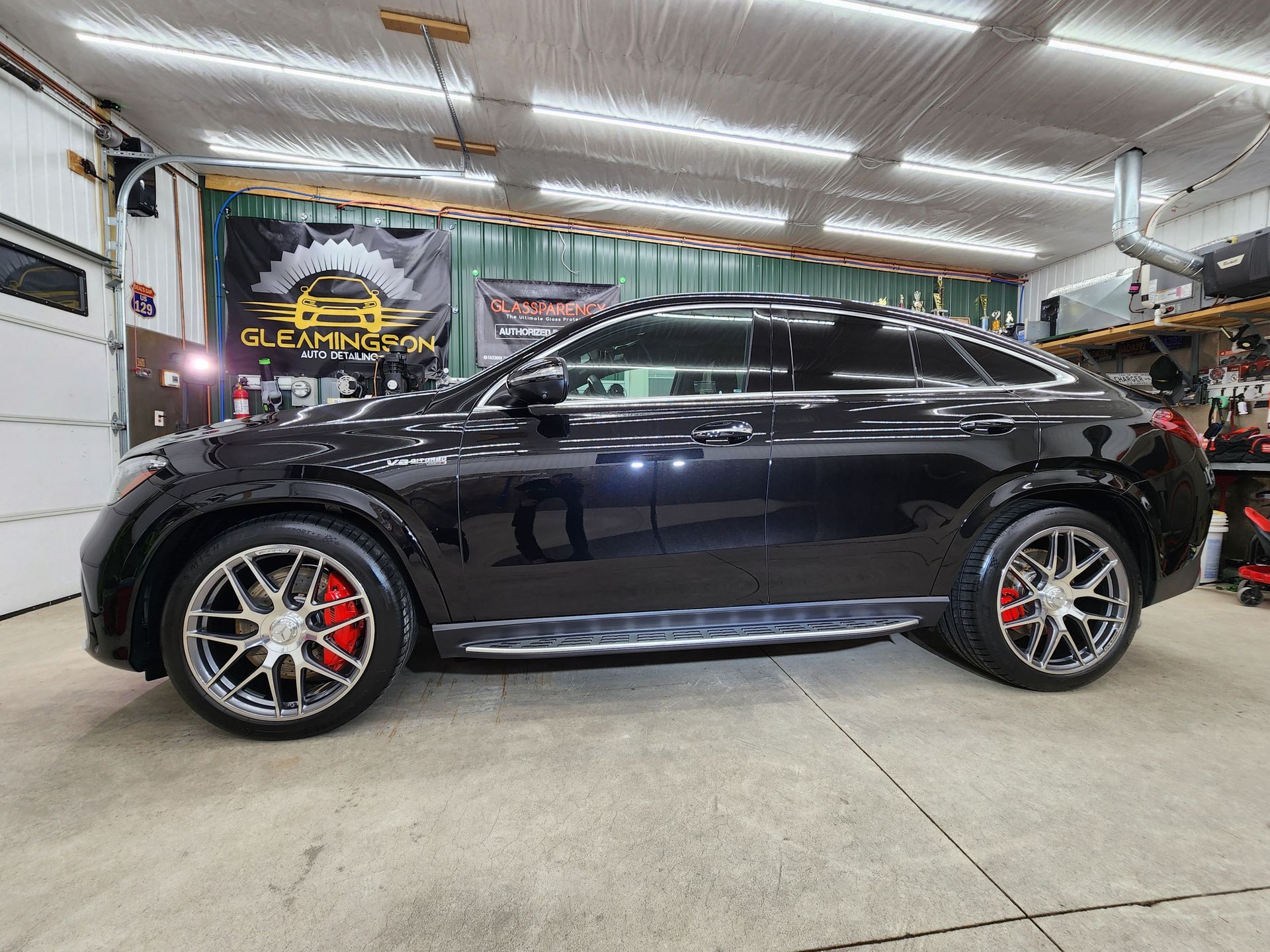Black SUV with chrome rims and red brake calipers in a garage.