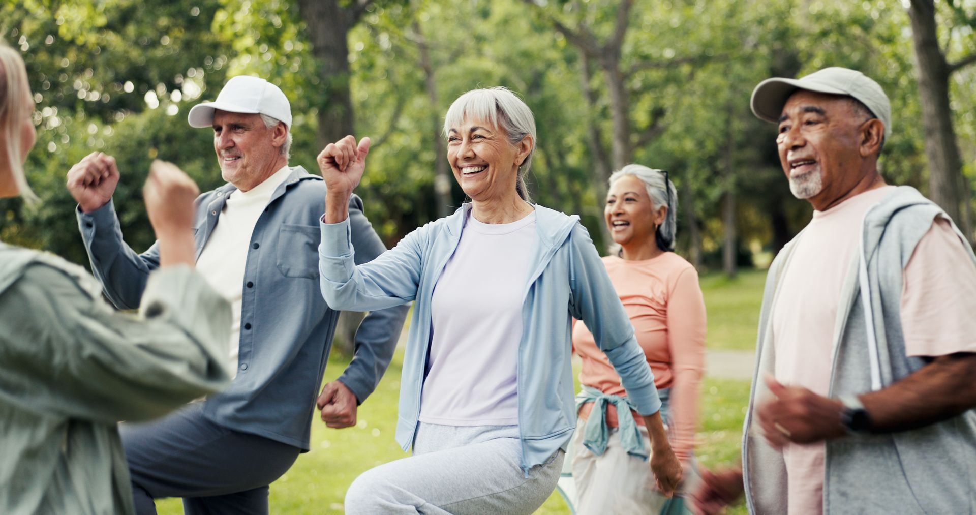 People exercising together in a park, smiling and lifting their knees during a group fitness session People exercising together in a park, smiling and lifting their knees during a group fitness session