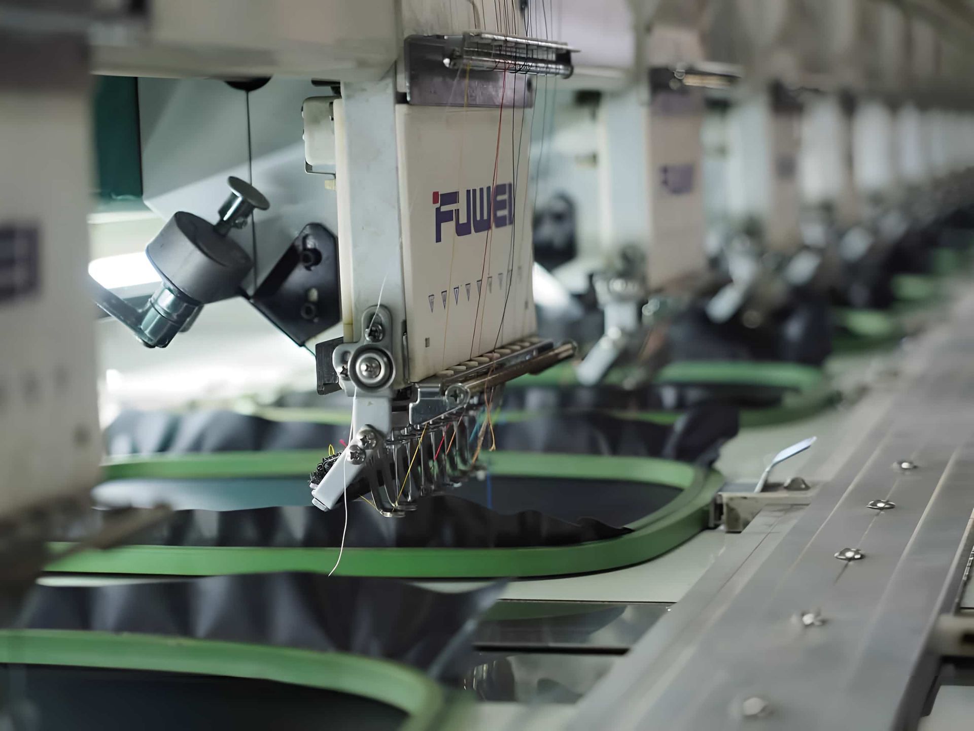 A Row Of Embroidery Machines Are Lined Up In A Factory — Gympie Embroidery Services In Southside, QLD