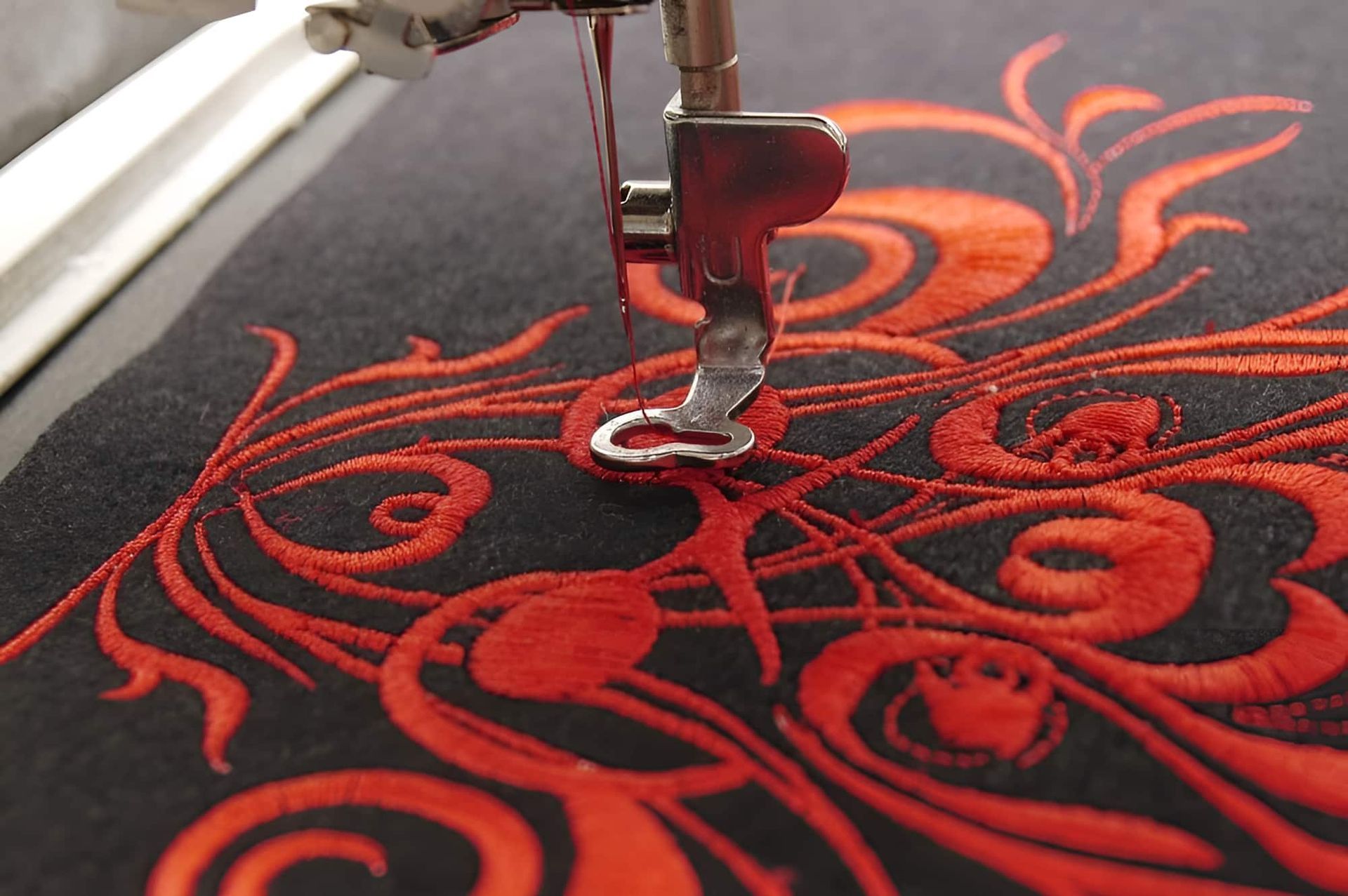 A Close Up Of A Sewing Machine With Red Embroidery — Gympie Embroidery Services In Southside, QLD