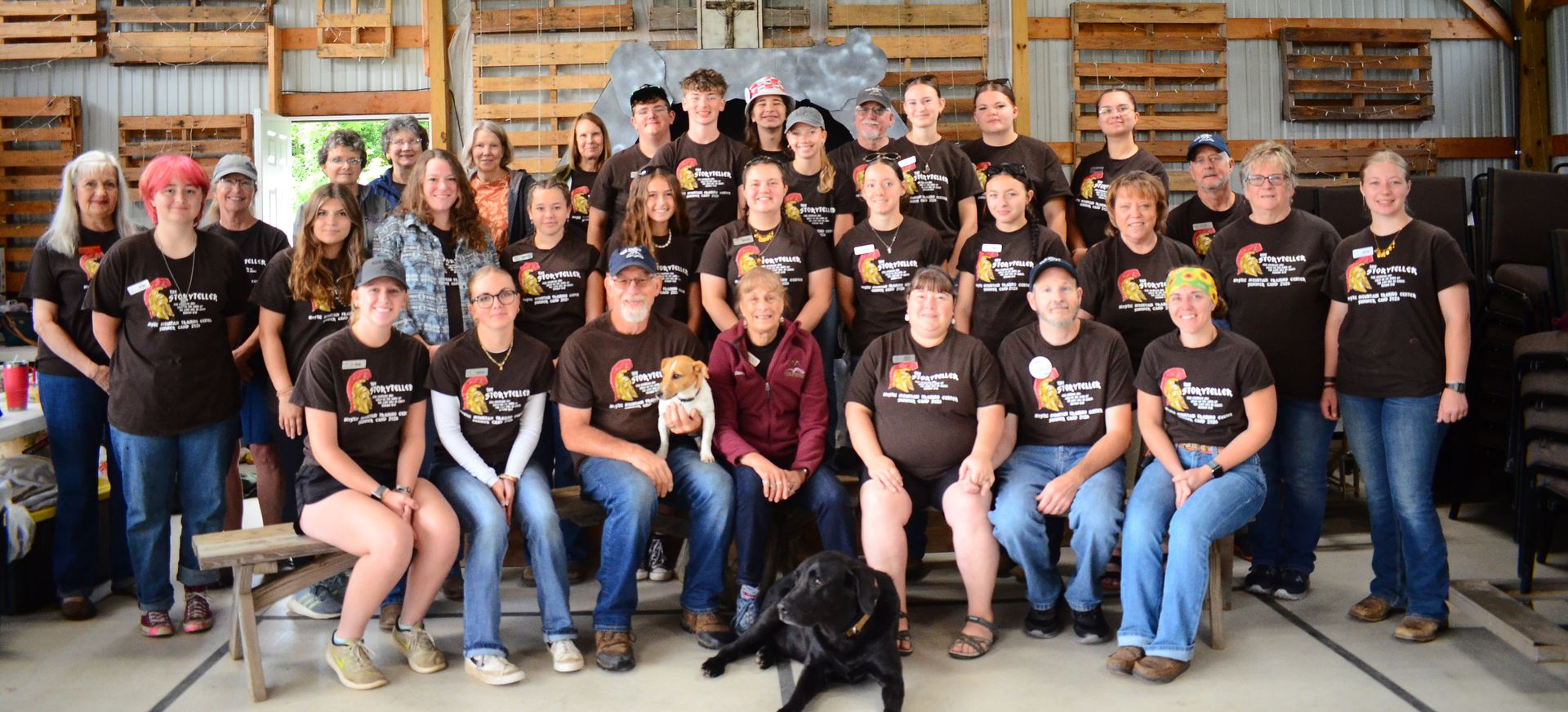 A group of people posing for a picture with a black dog