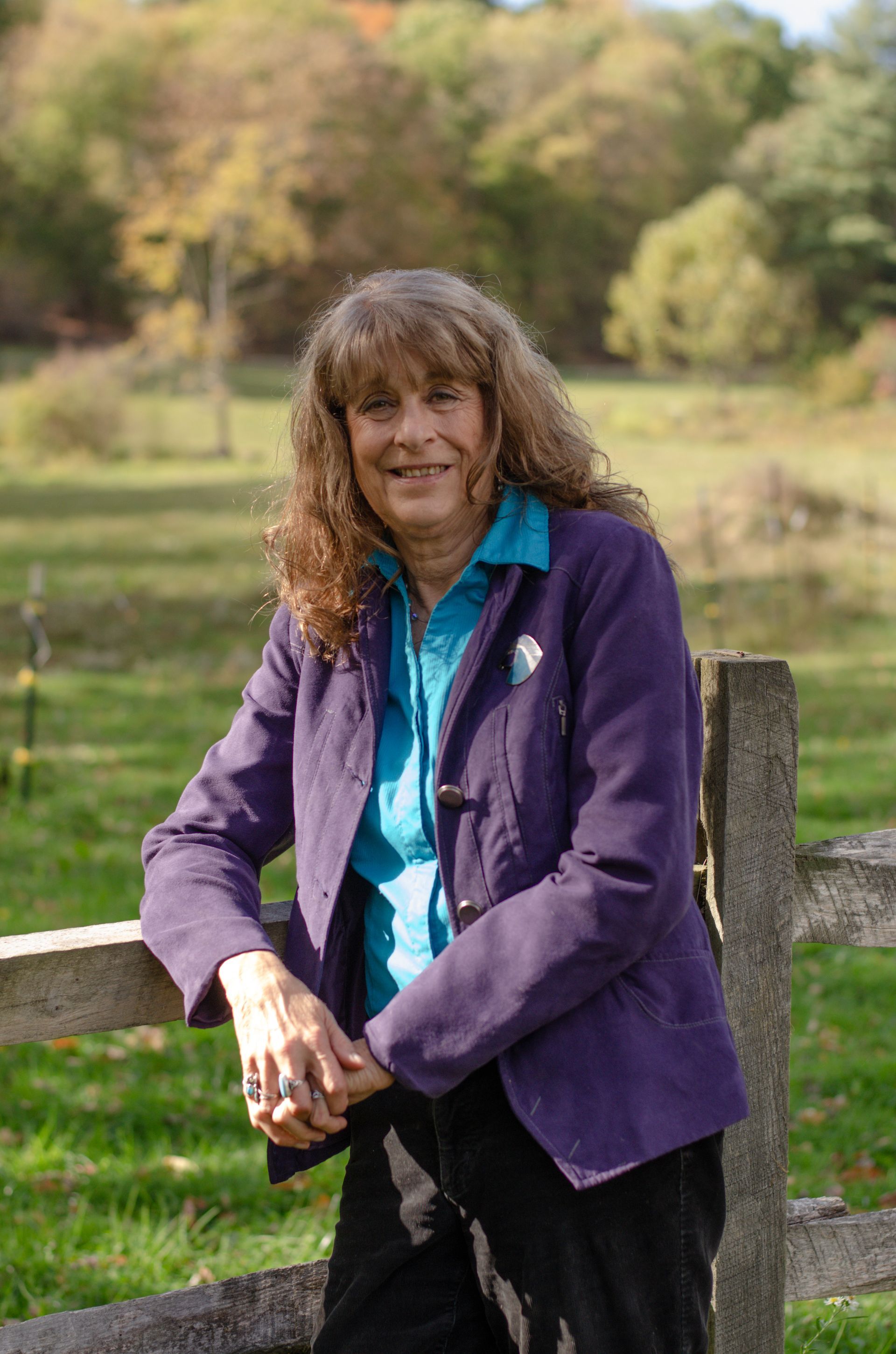 A woman in a blue shirt is hugging a black horse.