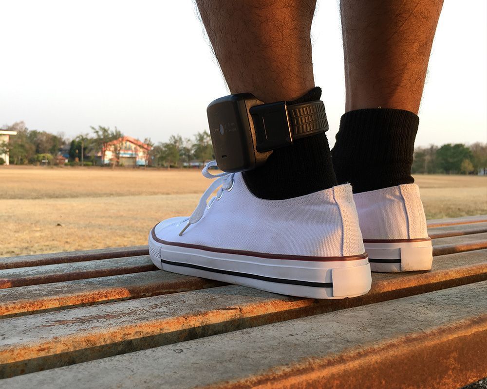 A person wearing white sneakers and black socks is standing on a bench.