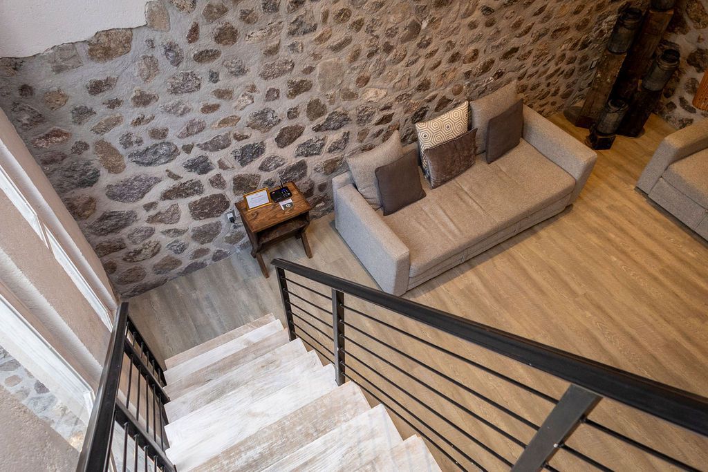 Staircase leading down to a living room with stone wall and light-colored sofa.
