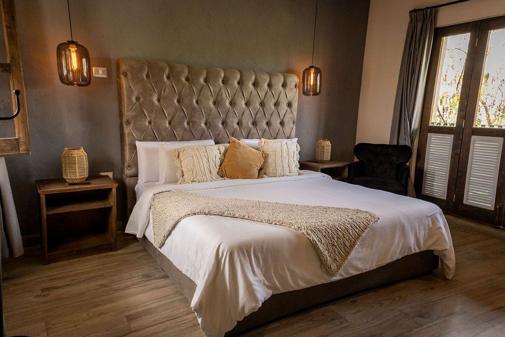 Bedroom with a tufted headboard, white bedding, nightstands, and pendant lights.