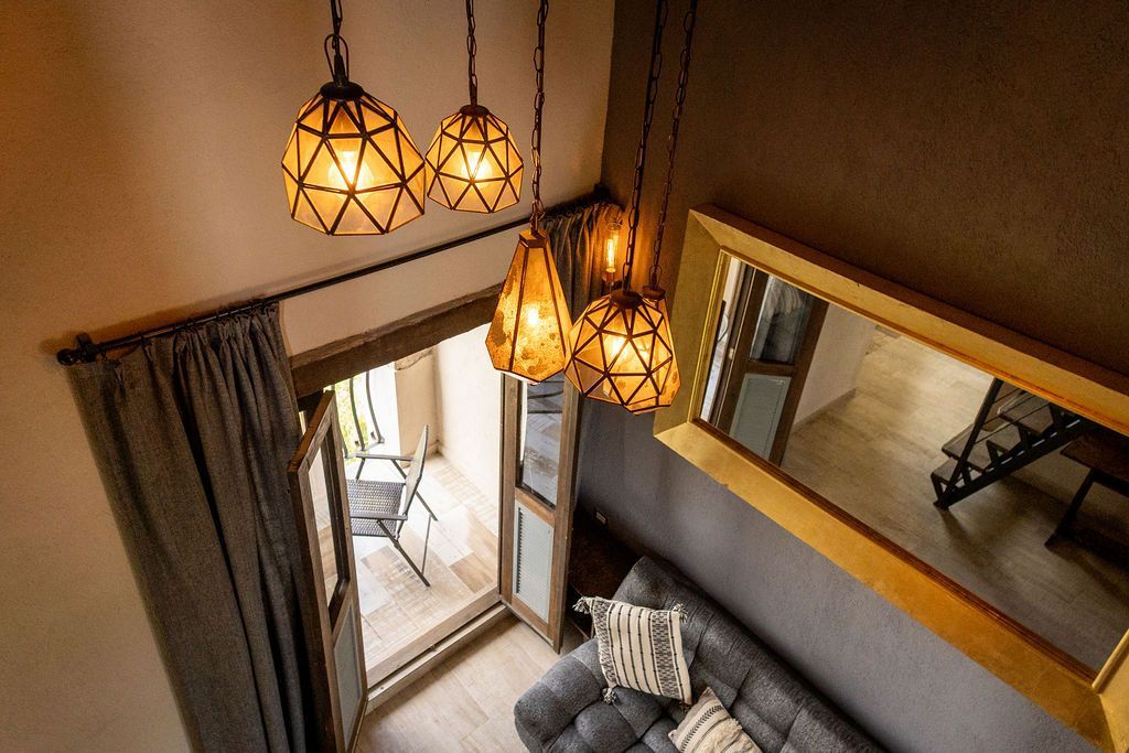 Overhead view of a room with hanging lamps, a couch, balcony door, and large mirror.