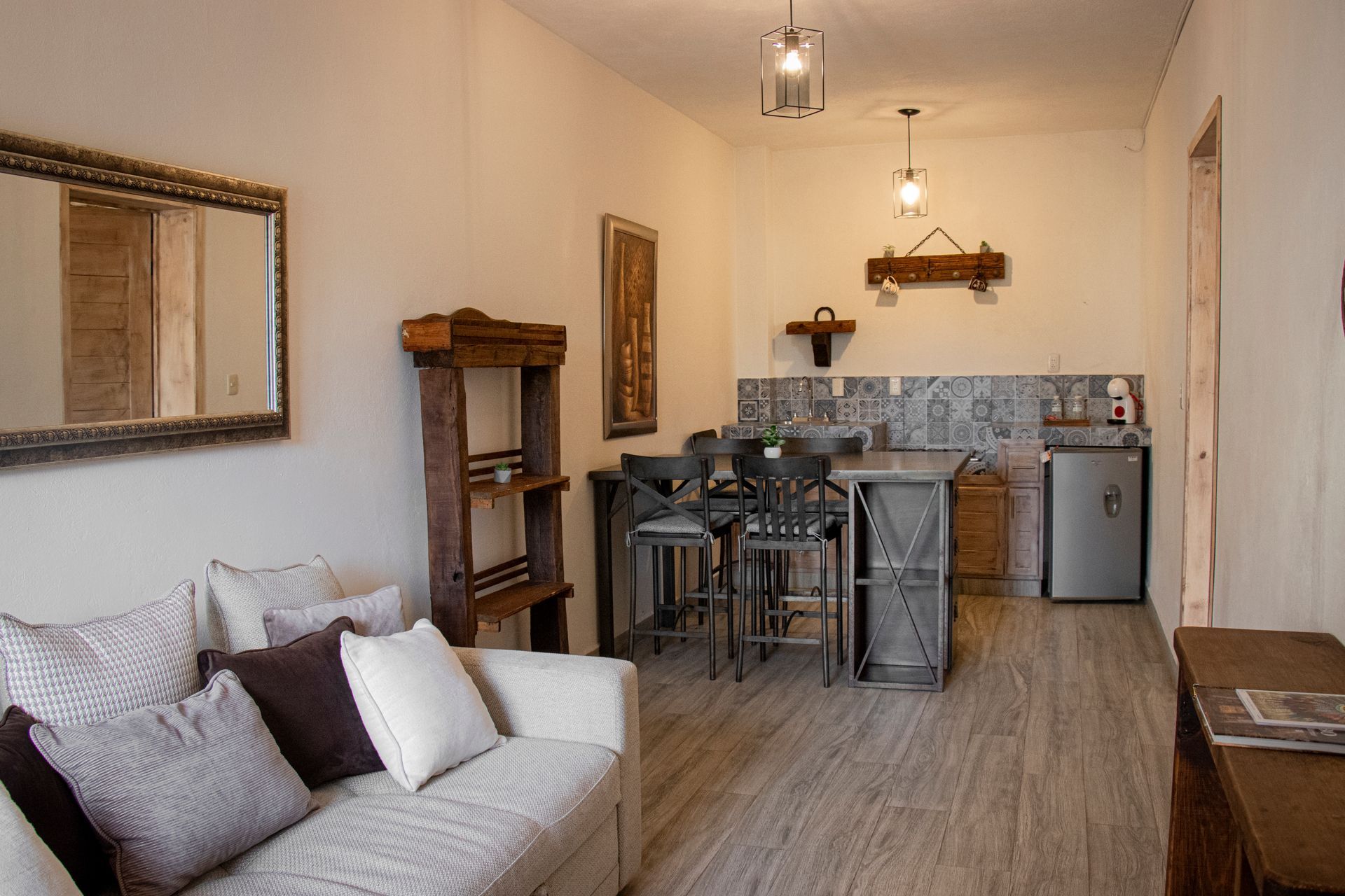 Cozy living space with sofa, wooden accents, small kitchen area, and a mini fridge.