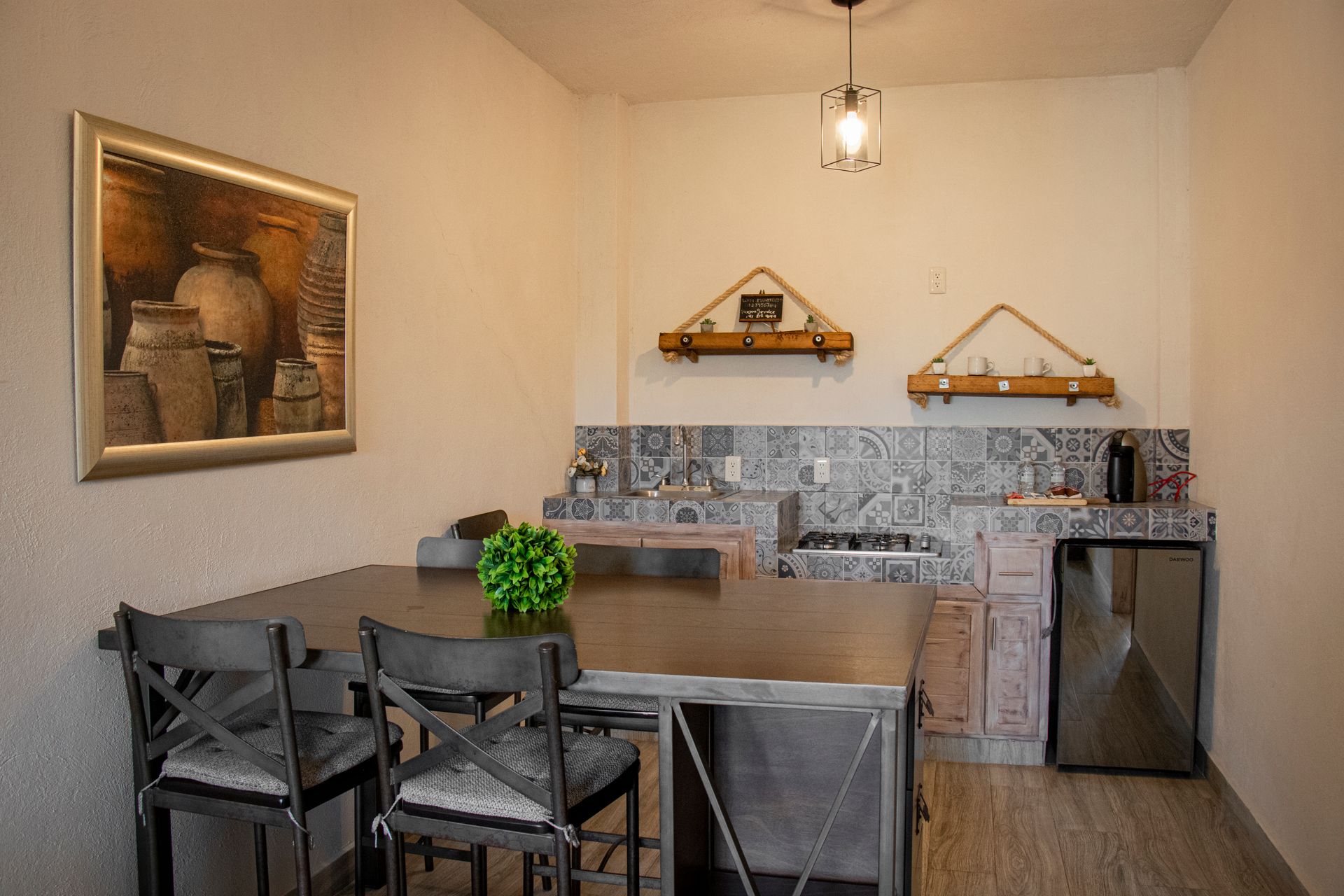Kitchen with a dining table, chairs, and built-in appliances; a painting on the wall.
