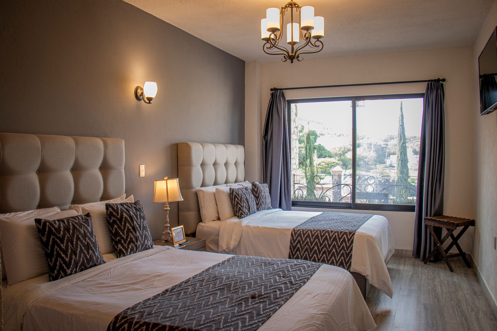 A hotel room with two beds, a window, and decorative lighting.