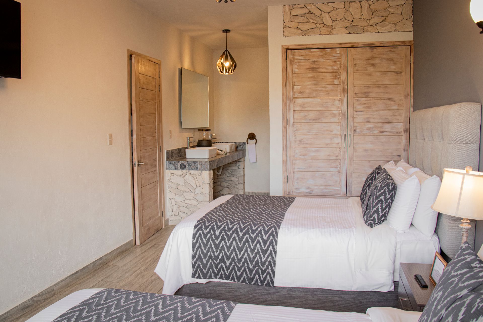 Bedroom with two beds, a bathroom, and a closet. Gray and white decor.
