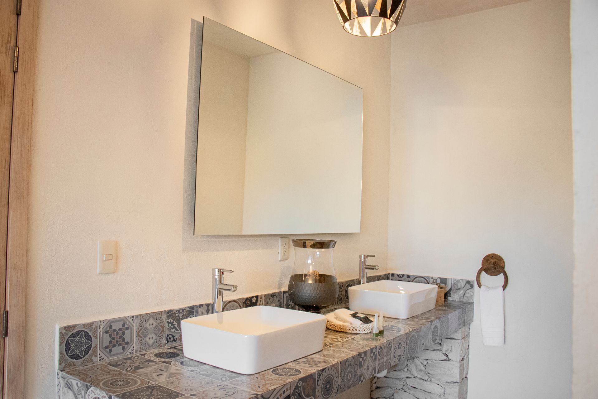 Bathroom with double sinks, large mirror, and gray countertop. Towel hanging on a round holder.