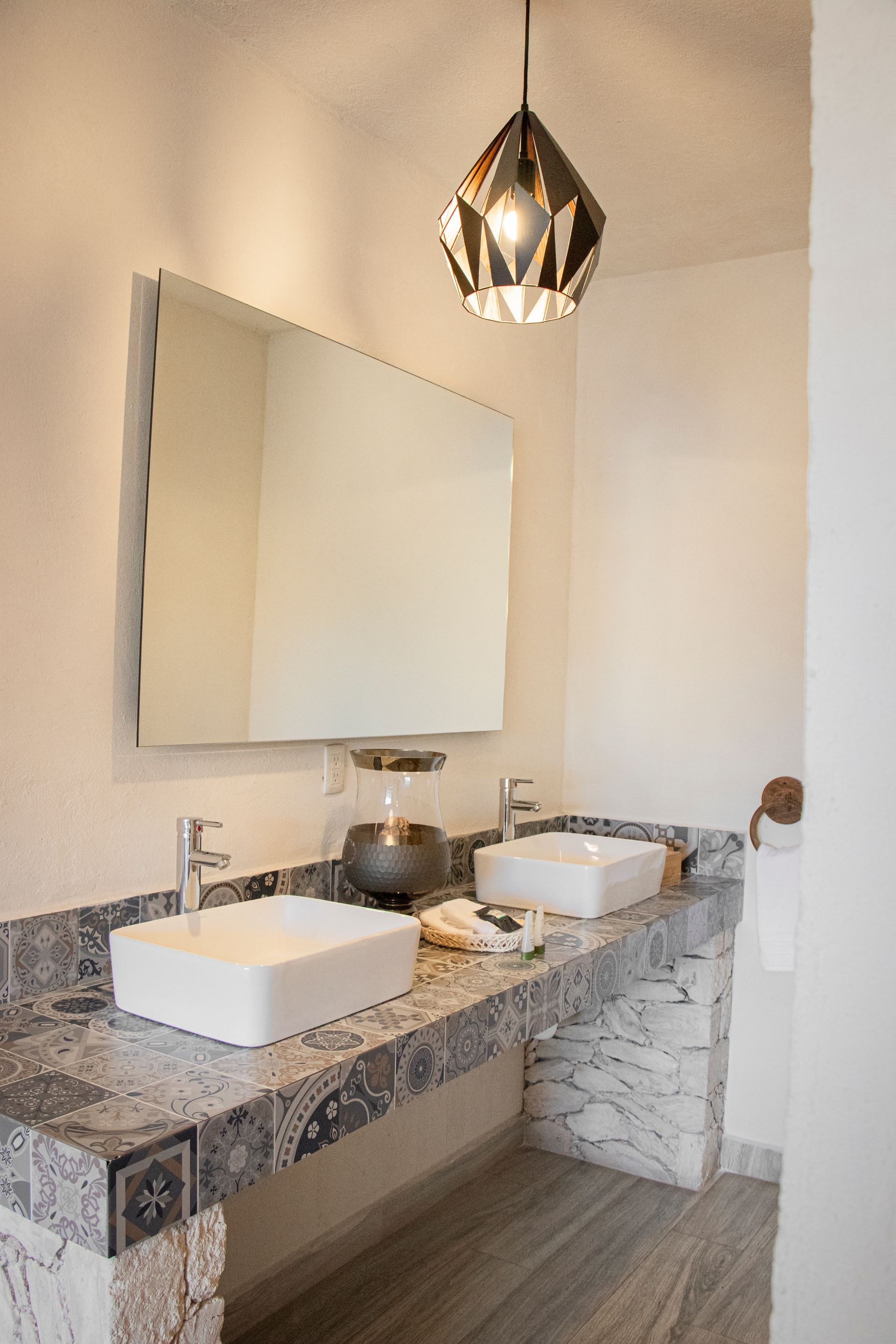 Bathroom with marble countertop, rectangular sinks, large mirror, and decorative hanging light.
