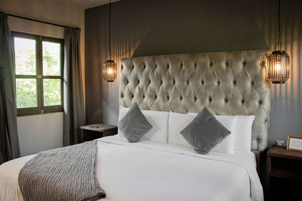 Bedroom with a tufted headboard, two pendant lights, and a window with natural light.