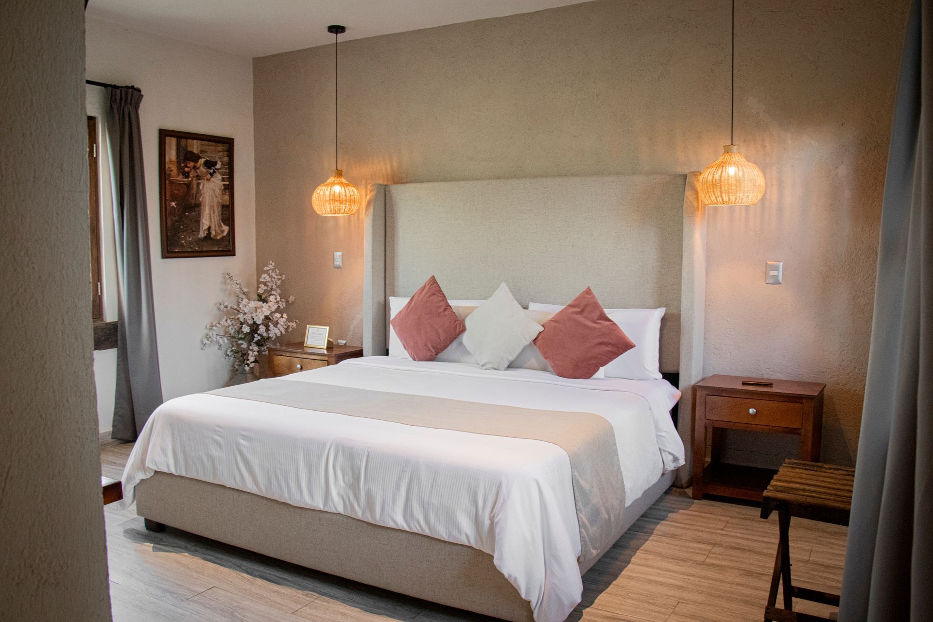 Bedroom with a large bed, pillows, nightstand, and two hanging lights.