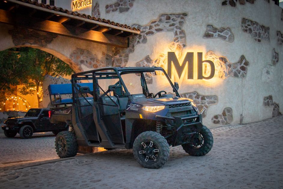 Off-road vehicle parked in front of a stone building with the letters 