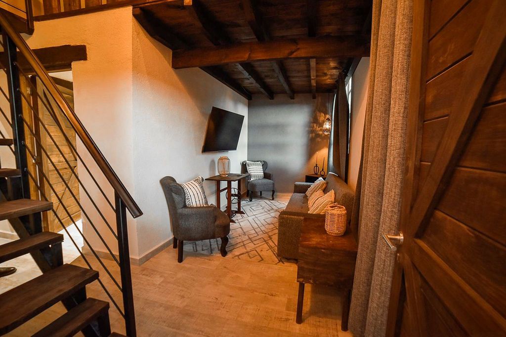 Interior view of a living space with wooden beams, stairs, and a sofa.
