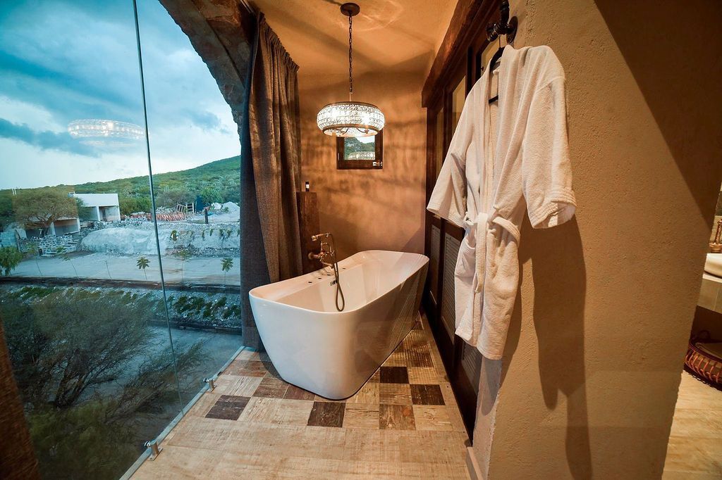 Freestanding bathtub on a balcony with a scenic view, a bathrobe hangs nearby.