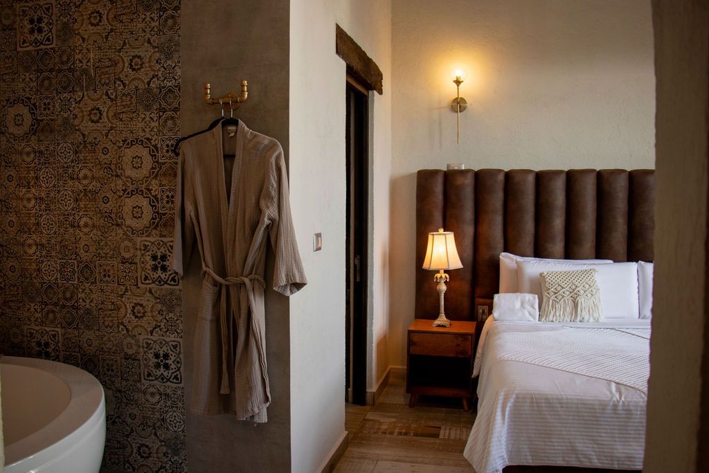 Bedroom interior with bed, nightstand, robe hanging on wall, and patterned tile.