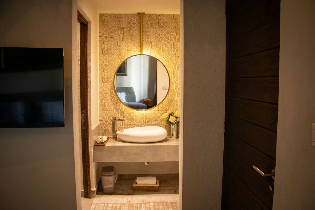 Bathroom with round mirror, sink, and decorative textured wall.