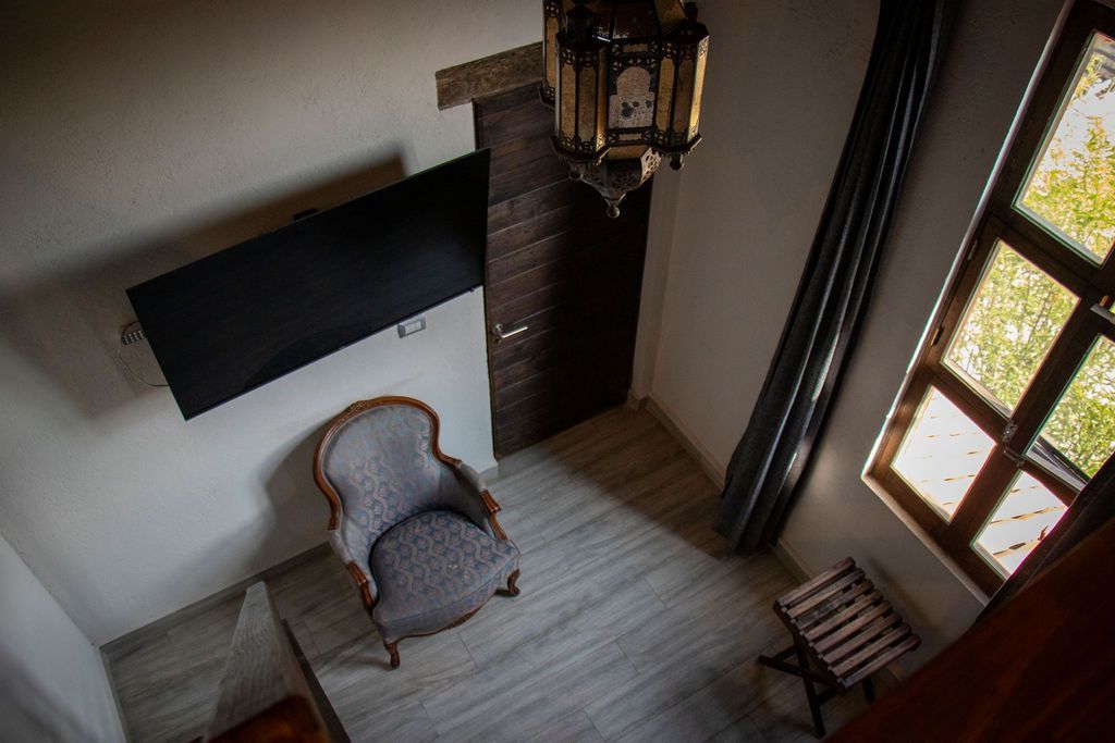 An overhead shot of a room with a TV, chair, ornate lantern, window, and a wooden door.