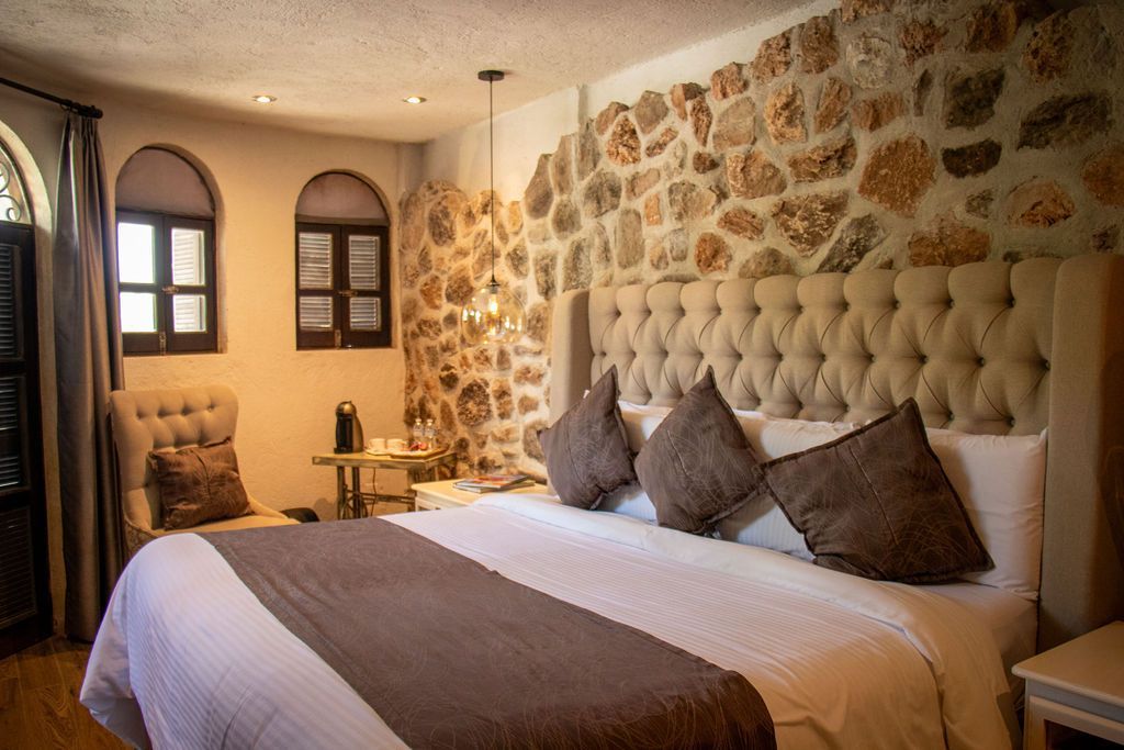 Bedroom with stone accent wall, large bed, and arched windows.