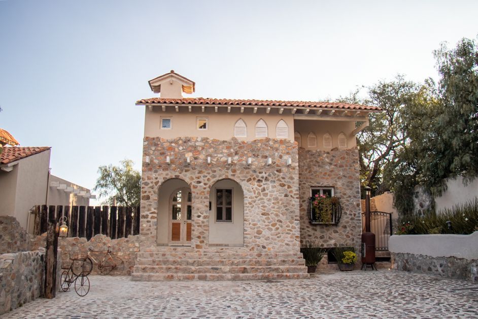Stone building with arches, tiled roof, small tower, and cobblestone courtyard.