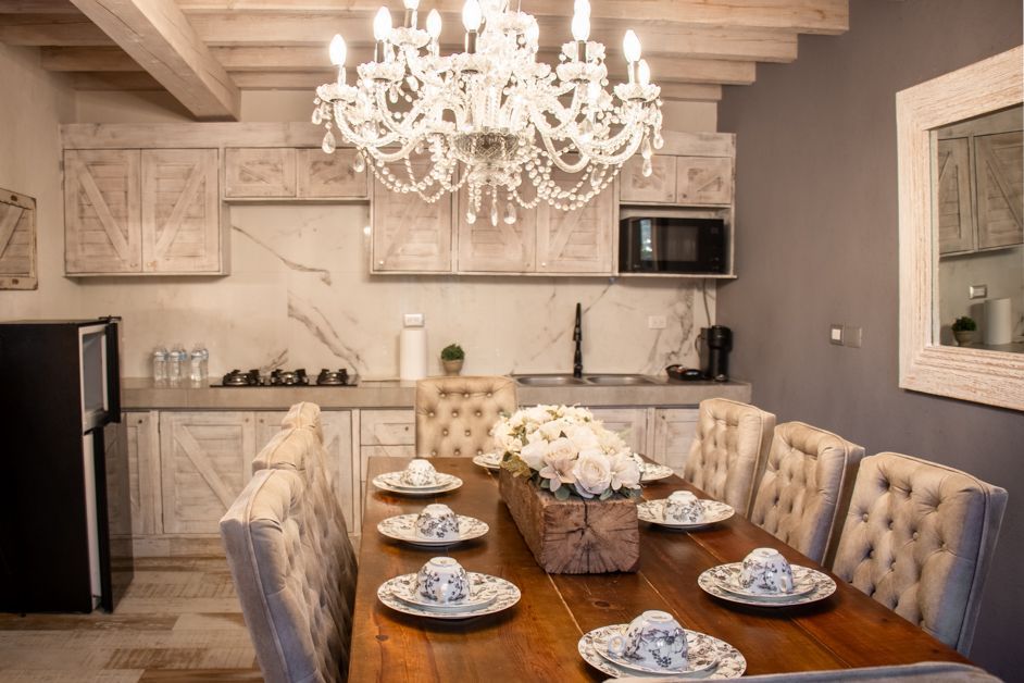 Kitchen with dining table set for guests, chandelier, and a refrigerator.