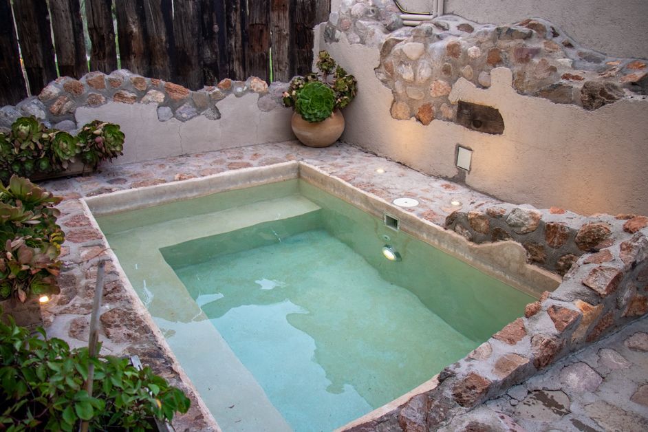 Small rectangular pool with steps, surrounded by stone and plants.