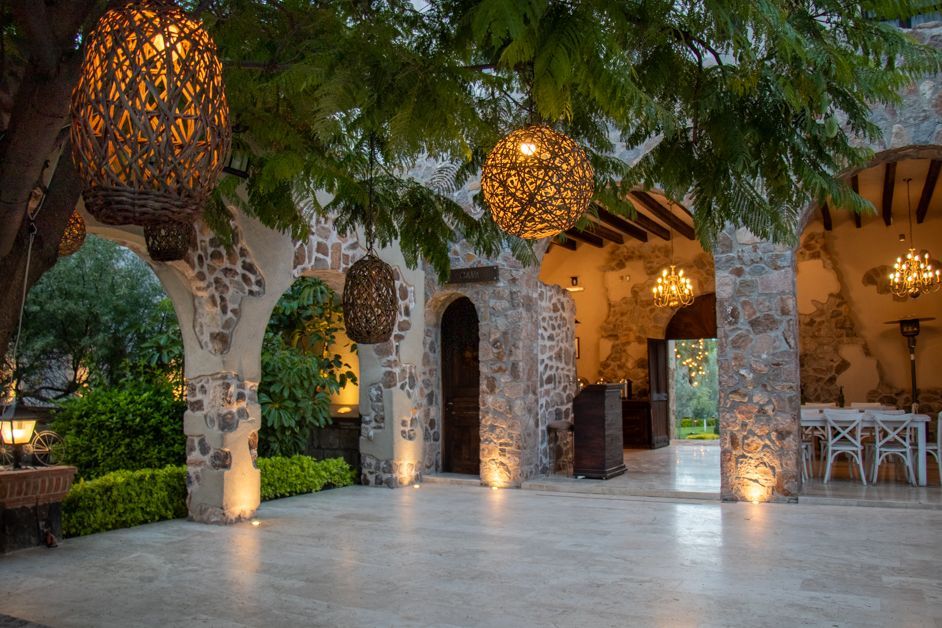 Outdoor stone patio with hanging woven lights, arches, and a table setting.