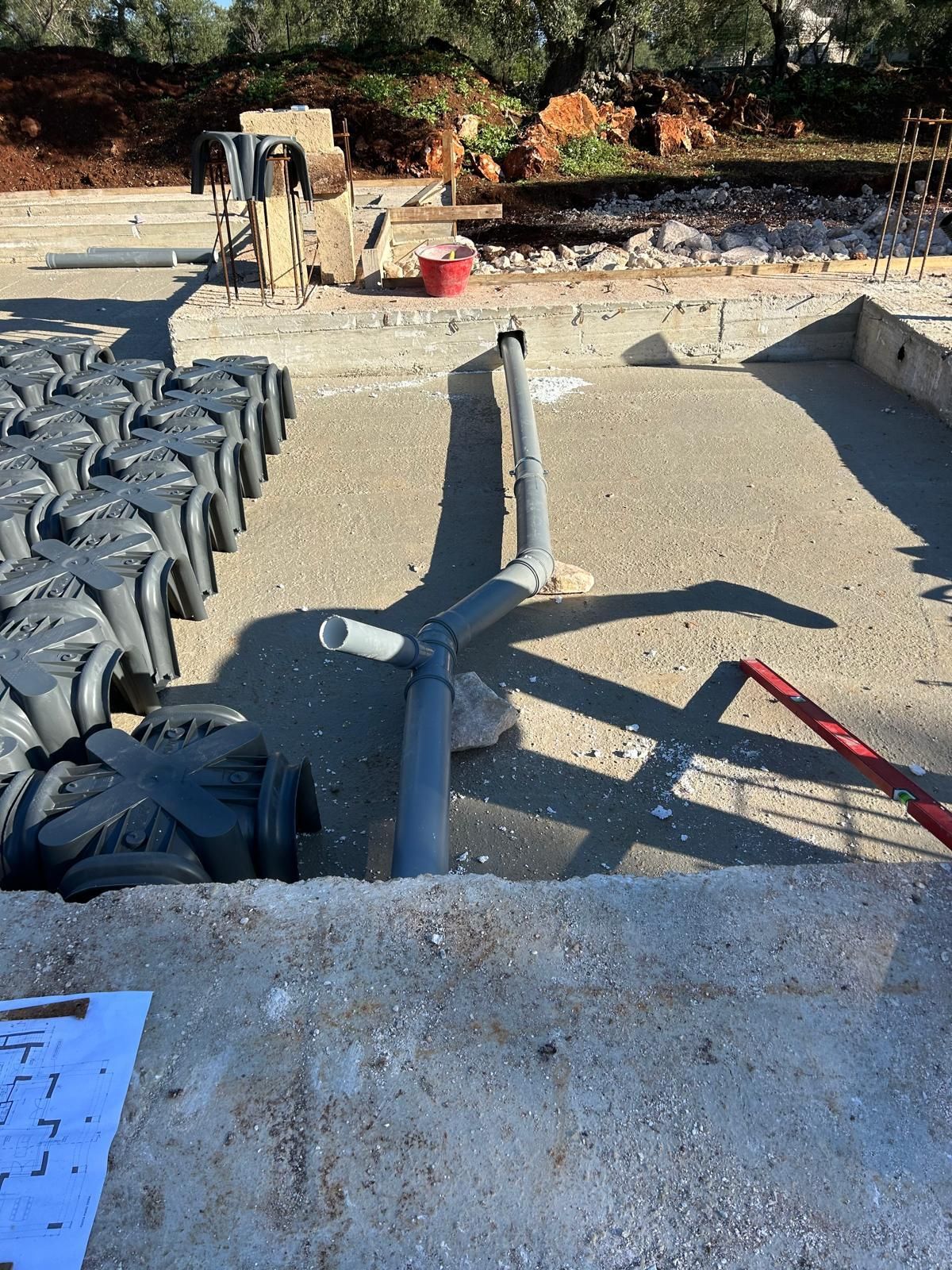 Cantiere edile con barre d'armatura e casseforme per il cemento in una cava di ghiaia, con operai sullo sfondo.