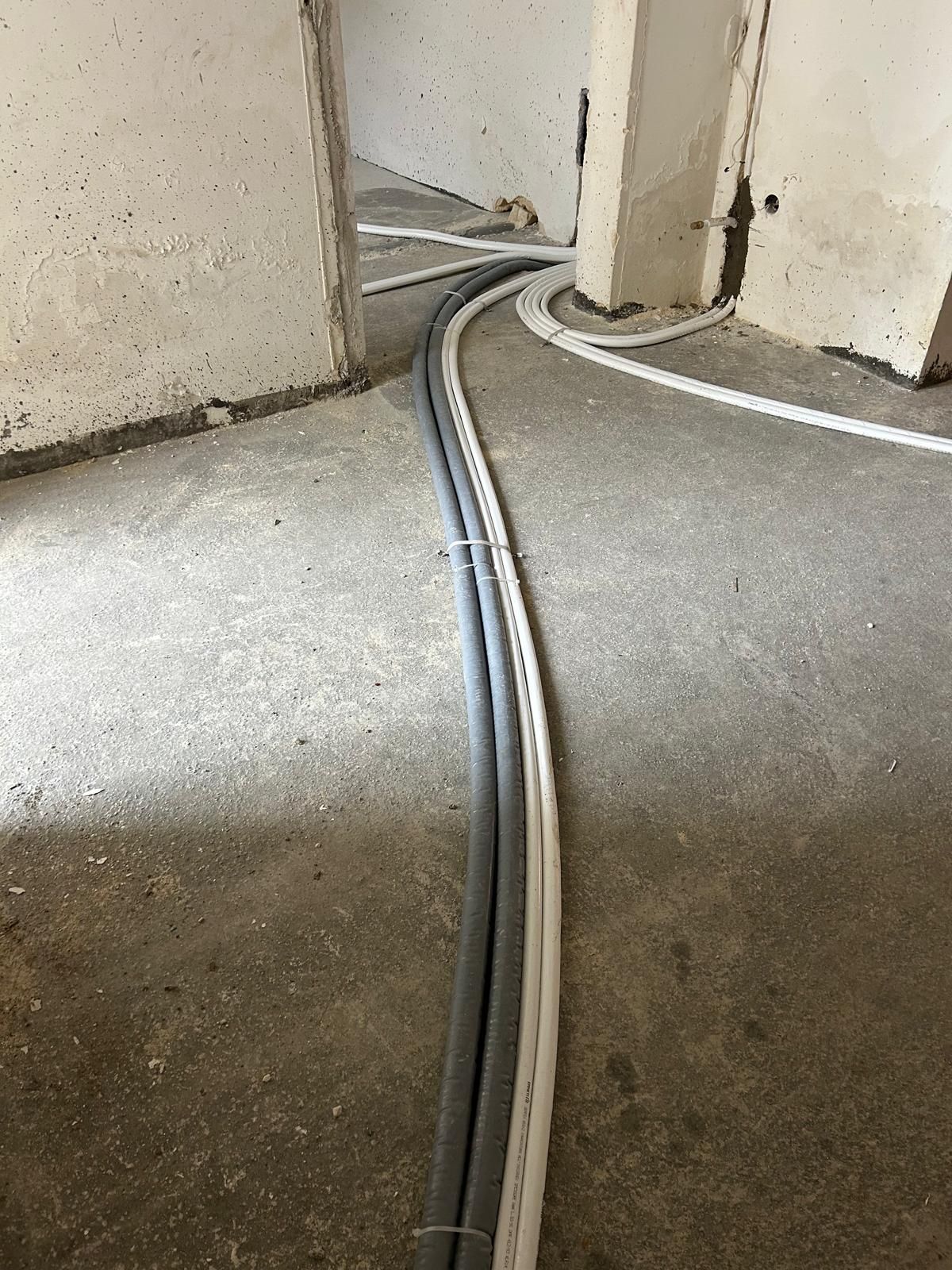 Cavi scoperti che corrono su un pavimento di cemento vicino a un'apertura nel muro.