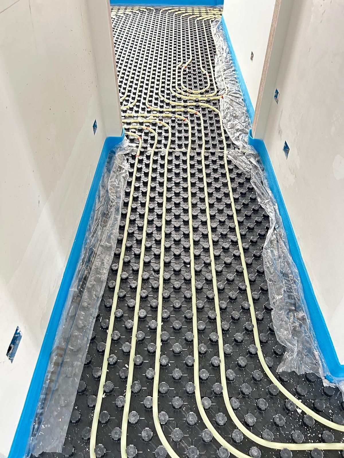 Pavimento del bagno irregolare con tubi del riscaldamento a pavimento e pannelli isolanti installati