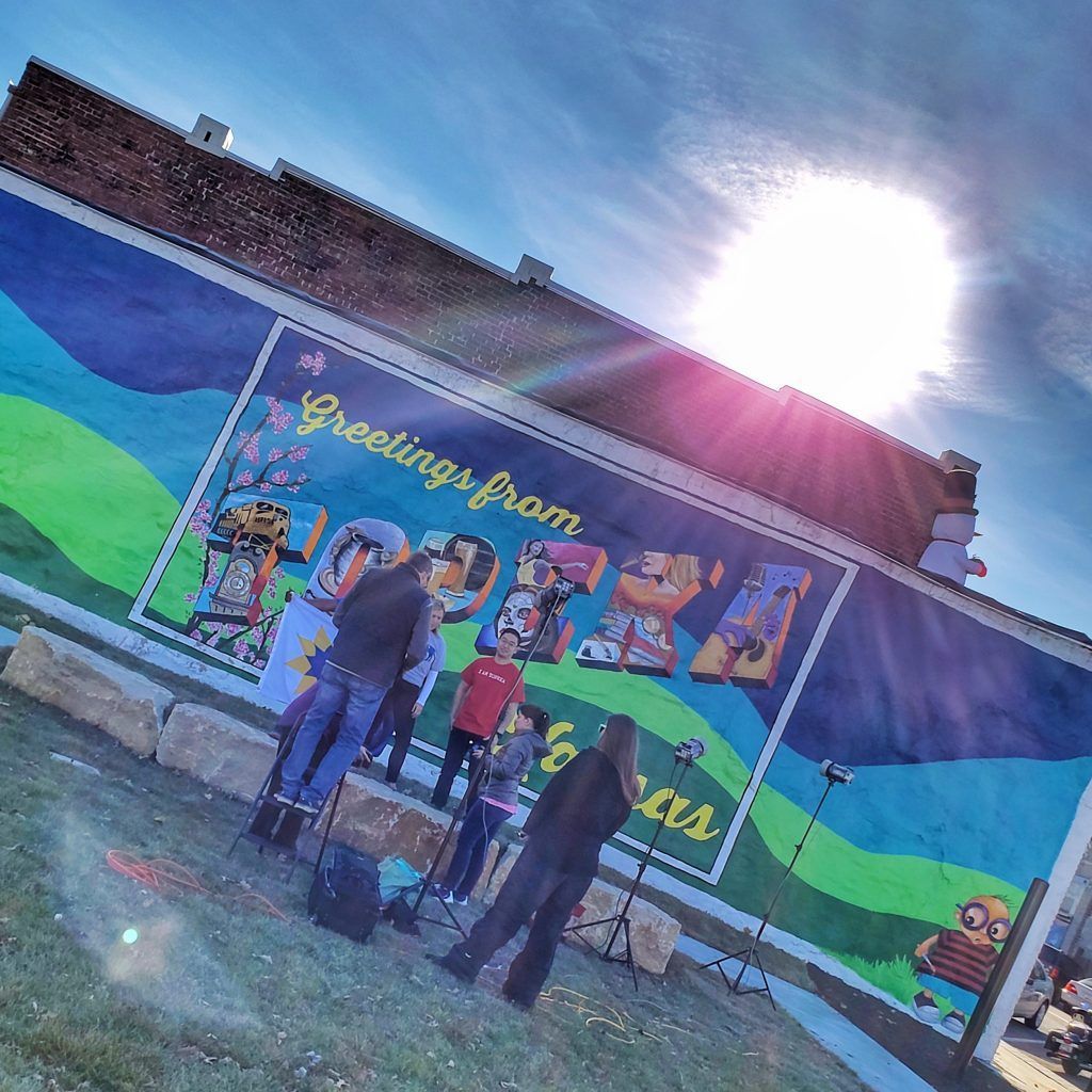 A group of people standing in front of a mural that says greetings from texas