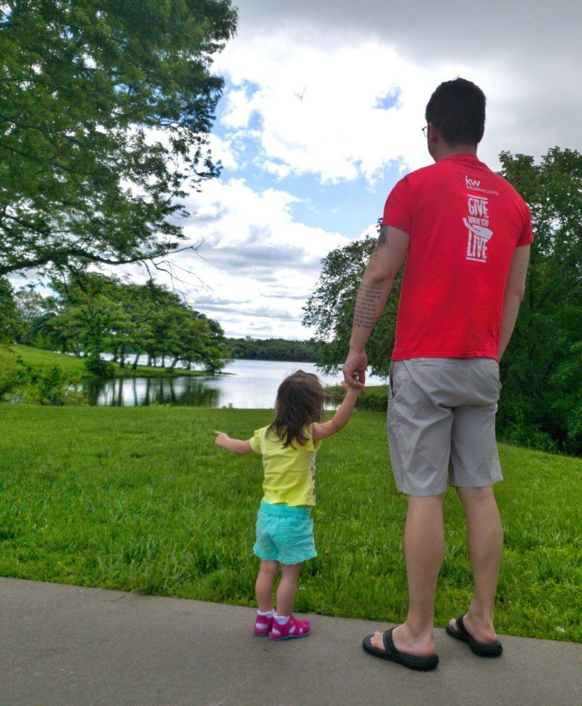 A man in a red shirt holds a little girl 's hand