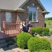 A family is standing in front of a brick house.