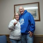 A man and a woman are posing for a picture in a room . the woman is holding a key.