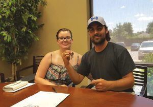 A man and a woman are sitting at a table holding keys.