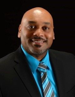 A man in a suit and tie is smiling for the camera.