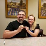 A man and a woman are posing for a picture while sitting at a table.