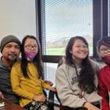 A group of people are sitting at a table in front of a window.
