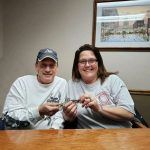 A man and a woman are sitting at a table holding keys.