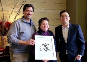 A woman is holding a framed picture with chinese writing on it