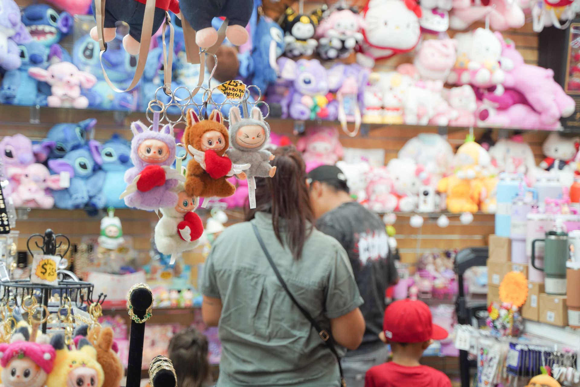 People browsing a shop filled with plush toys and keychains.