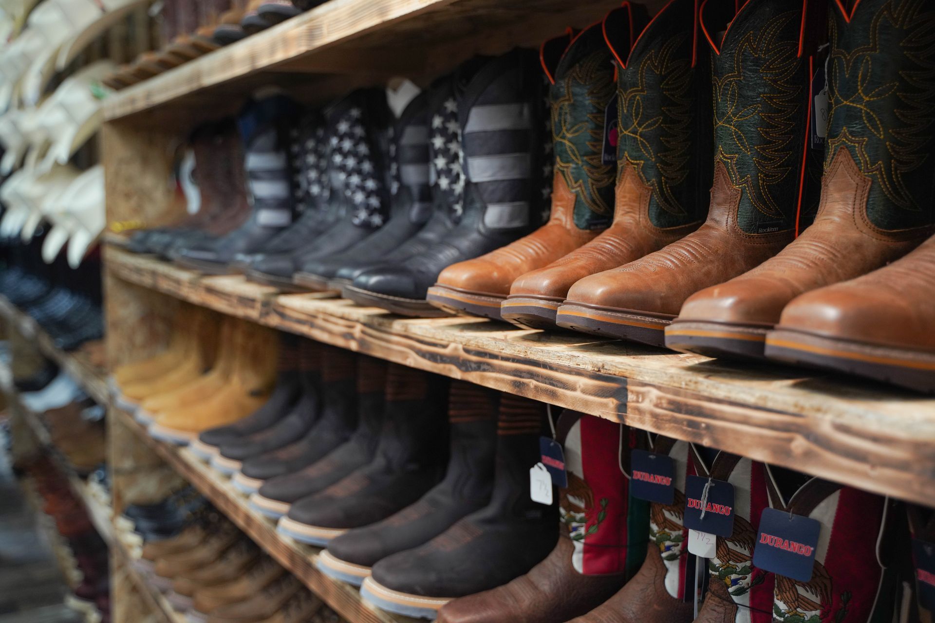 Shelves displaying rows of leather cowboy boots in various colors and styles.